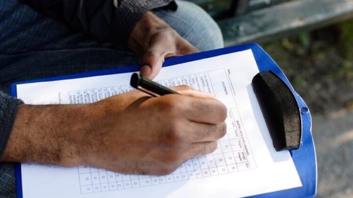 A close-up of a person checking off a list on a clipboard.